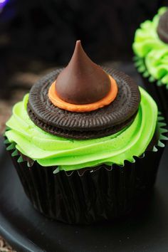 two cupcakes with green frosting and a chocolate top on a black plate