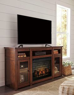 a flat screen tv sitting on top of a wooden entertainment center next to a fire place