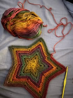 two crocheted stars on a bed next to yarn