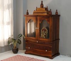 a wooden cabinet sitting on top of a white floor next to a potted plant