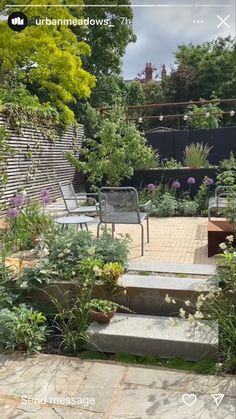 a garden with steps leading up to the back yard and seating area, surrounded by greenery