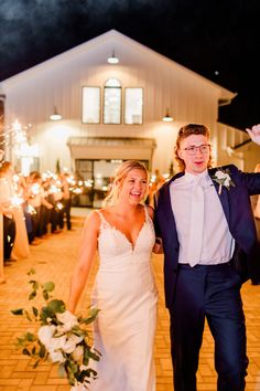 a bride and groom walk through sparklers at their wedding