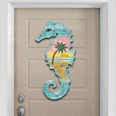 a door decorated with a sea horse and palm tree on the beach in front of it