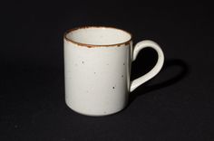 a white coffee cup with rusted edges on a black background