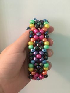 a hand holding a cell phone case made out of beads and plastic balls on it