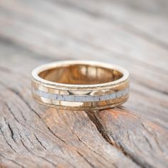 two wedding bands are sitting on top of a piece of wood