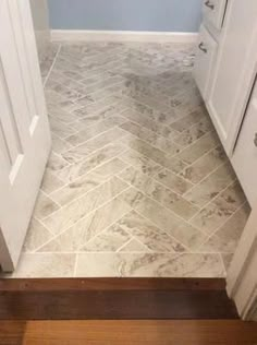 a bathroom with blue walls and white cabinets next to a wood floor that has a herringbone pattern on it