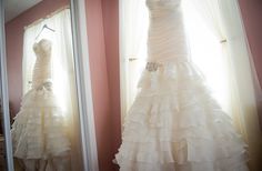 a wedding dress hanging in front of a mirror