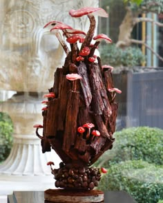 the sculpture is made out of wood and has red mushrooms growing on top of it