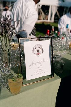 a dog is sitting on the table at a party with people in the background and there is a sign that says happy june