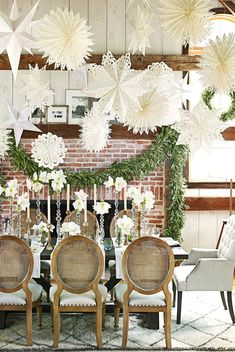 a dining room table with chairs and paper snowflakes hanging from the ceiling