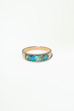 a gold ring with blue opal inlays on the outside and inside, against a white background