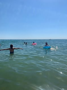 several people in the water with surfboards on their backs and one person holding his arms out