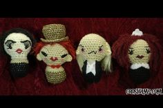 five crocheted dolls are lined up on a red surface, one is wearing a top hat