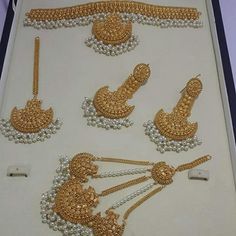 an assortment of gold and white beaded items in a display case on a table