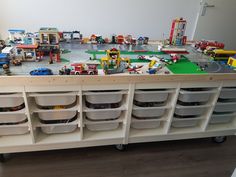 a toy train table with legos on the top and many other toys in bins