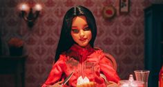 a doll is sitting at a table with a knife and fork in her hand,