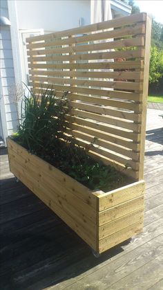 a wooden planter box with plants growing in it on a deck next to a house