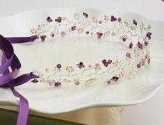 a white plate topped with a purple ribbon and flowered headband on top of a table