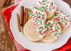 some cookies and cinnamon sticks on a white plate with red and green sprinkles