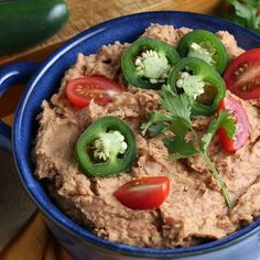 a blue bowl filled with hummus and tomatoes