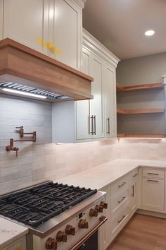 a stove top oven sitting inside of a kitchen next to white cupboards and drawers