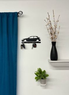 a black car key holder on the wall next to a blue curtain and a plant