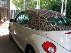 the back end of a white car with a leopard print covering on it's hood