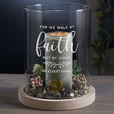 a glass candle holder with rocks and succulents in it that says, for we walk by faith not by sight