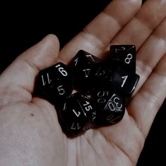 a hand holding black dices with numbers on them