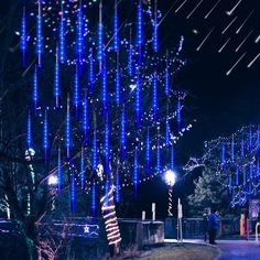 the trees are decorated with blue lights and streamers in the night sky, as well as stars