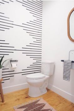 a white toilet sitting next to a sink in a bathroom under a mirror and towel rack