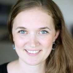 a close up of a person with long hair and blue eyes smiling at the camera