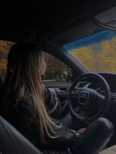 a woman sitting in the driver's seat of a car, looking out the window