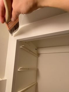 a person is brushing the bottom of a closet door with a toothbrush and brush