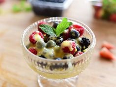 a small glass bowl filled with fruit and mint garnish on top of a wooden table