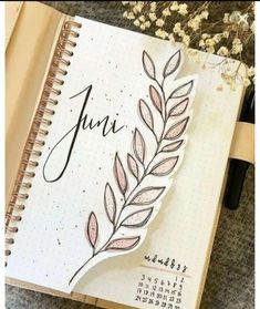 an open spiral notebook with the word june written on it and a leaf drawn in ink