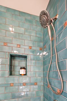 a shower head with two bottles on it in a blue tiled bathroom area, next to a window