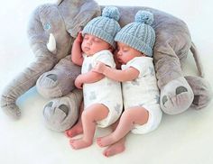 two baby babies are sleeping next to an elephant stuffed animal that looks like it's laying on top of each other