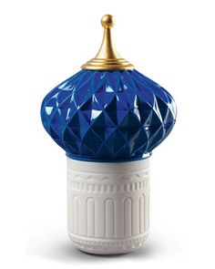 a blue and white vase with a gold top