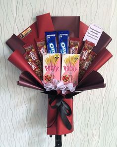 a bouquet of chocolates and candy bars wrapped in red paper on a white wall