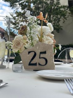 there is a vase with flowers in it and the number twenty five sits on the table