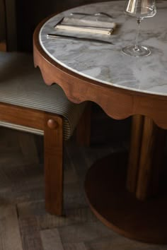 a wine glass sitting on top of a marble topped table next to a wooden chair