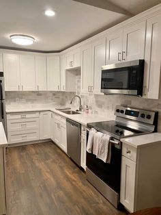 a kitchen with white cabinets and stainless steel stove top oven, dishwasher and microwave