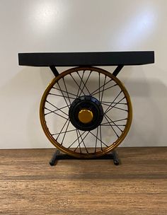 a table that has a wheel on it and is sitting on top of a wooden floor