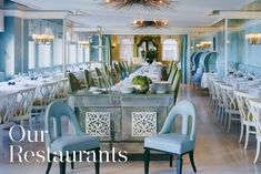 a dining room filled with lots of white tables and chairs covered in blue cloths