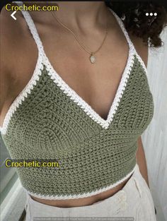 a woman wearing a green and white crocheted top with her hand on her hip