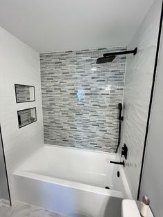 a white bath tub sitting inside of a bathroom next to a toilet and shower head