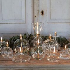 several clear glass candlesticks sitting next to each other in front of a white door