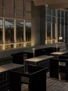 an empty restaurant with tables and chairs in front of large windows at night, lit by lamps